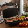 A grill with burgers and sausages on it, set in a kitchen environment. Produktbild-Vorschau