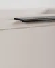 A close-up shot of a black cabinet handle on a beige cabinet. Produktbild-Vorschau