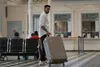 A man is pulling a suitcase through a train station or airport terminal. Produktbild-Vorschau