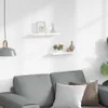 Two white wall shelves are mounted on a white wall above a gray sofa with two pillows. A pendant lamp hangs to the left. Náhľad obrázku produktu