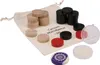 A collection of carrom game pieces, including wooden, black, and red discs, along with a decorative purple and white striker, are arranged on a beige drawstring bag. Produktbild-Vorschau
