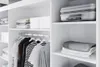 A clean, modern closet interior with shelves and a hanging rack. Produktbild-Vorschau