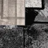 A close-up view of a rug with abstract geometric patterns in gray, black, and white. Produktbild-Vorschau