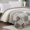 A close-up view of a quilted bedspread on a bed. Náhled obrázku produktu