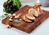A roasted meat roll and ingredients are arranged on a wooden cutting board. Produktbild-Vorschau