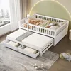 A white wooden daybed with a pull-out trundle bed and storage drawers, set up in a bedroom with a large window and a green curved wall. Produktbild-Vorschau