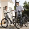 A man and a woman standing next to two electric bicycles. Produktbild-Vorschau