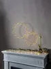 Two LED light rings are suspended above a fireplace mantel decorated with a string of lights and greenery. Podgląd zdjęcia produktu