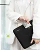A person is holding a black laptop sleeve with a smartphone partially inserted into a front pocket. Produktbild-Vorschau