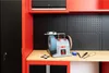 A wet/dry sharpening machine is placed on a workbench in a workshop setting, with cabinets and pegboard in the background. Anteprima dell’immagine prodotto