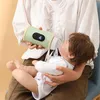 A person is holding a baby and feeding it from a bottle warmer. Produktbild-Vorschau