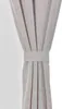 A close-up of a light-colored curtain held back by a fabric tie. Produktbild-Vorschau
