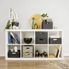 A white cube shelf unit filled with various storage baskets, books, decorative items, and wine bottles. Voir les images du produit