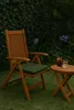 A wooden chair and small table with drinks on it, set up on a lawn in a garden. Produktbild-Vorschau