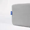 A close-up of a light gray fabric product with a blue tag attached to the side. Náhled obrázku produktu