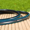A garden hose coiled on a wooden deck with grass in the background. Voir les images du produit