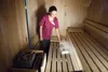 A woman is cleaning a wooden sauna bench with a steam cleaner. Voir les images du produit