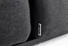 Close-up of a dark gray fabric cushion with a white brand logo on the side, resting on a dark metal frame. Produktbild-Vorschau