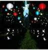 A pathway lined with trees and illuminated by colorful lanterns and fairy lights. Podgląd zdjęcia produktu