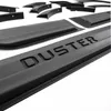 A close-up, angled view of black car fender flares and door edge guards, with the word "DUSTER" embossed on one of the pieces. Náhľad obrázku produktu