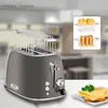 A toaster with a bread rack and a small plate of cheese and bread in the foreground, set against a blurred kitchen background. Náhled obrázku produktu