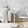 A white stand fan is shown in a living room setting next to a sofa and a chair, with stylized air currents emanating from the fan. Voir les images du produit