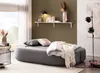 A bedroom scene with a sofa, shelf, lamp, and floor lamp. Produktbild-Vorschau