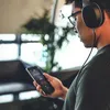 A person wearing headphones is looking at their smartphone. Anteprima dell’immagine prodotto