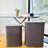 Two laundry baskets are placed on a wooden floor in front of an ironing board with towels and a plant on it. Produktbild-Vorschau