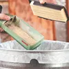 A person is emptying sawdust from a Bosch dust collector into a trash can, while holding a filter. Podgląd zdjęcia produktu