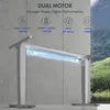 A dual motor electric standing desk frame is shown in a modern setting with a concrete wall and a natural landscape visible through a window. Produktbild-Vorschau