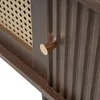 A close-up view of a dark walnut cabinet with a gold knob and a rattan insert. Podgląd zdjęcia produktu