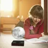A young girl is lying on the floor reading a book next to a levitating moon lamp. Náhled obrázku produktu