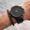 A close-up shot of a person's wrist wearing a black Tommy Hilfiger watch and a black beaded bracelet. Náhled obrázku produktu