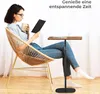A woman sits in a chair reading a book and holding a mug, with a laptop stand next to her. Produktbild-Vorschau