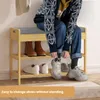 A person is sitting on a shoe bench and tying their shoes. The shoe bench has shelves for shoes. Produktbild-Vorschau