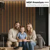 A family of three is sitting on a couch in a modern living room with wood slat wall paneling. Náhľad obrázku produktu