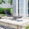A dark gray chaise lounge is set up on a wooden deck with a rug underneath, next to a large glass door and some greenery. Produktbild-Vorschau