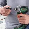 A person is holding a cordless impact wrench and a socket adapter, preparing to attach the adapter to the wrench. Náhľad obrázku produktu