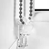 Close-up of a clear plastic bracket holding a beaded cord for a window blind. Produktbild-Vorschau