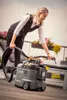 A woman is cleaning an outdoor bench with a Kärcher Puzzi 9/1 BP Waschsauger. Produktbild-Vorschau