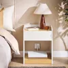 A bedside table with a lamp, book, and glass of liquid next to a bed. Produktbild-Vorschau