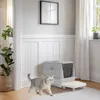A cat walks in front of a litter box in a well-lit room with a plant and a framed picture on the wall. Náhľad obrázku produktu