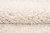 A close-up view of a beige shaggy rug, showing its texture and fibers. Náhľad obrázku produktu