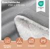 A close-up of a gray and white fluffy blanket, with icons and text indicating its features and uses. Voir les images du produit
