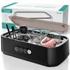 An ultrasonic cleaner with various items inside, with its packaging in the background. Produktbild-Vorschau
