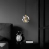 A pendant light hangs above a bedside table with an alarm clock and books. Podgląd zdjęcia produktu