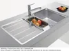 A stainless steel kitchen sink with a faucet and a small bowl of fruit. Produktbild-Vorschau