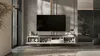 A modern living room with a wall-mounted TV and entertainment unit, with a bedroom visible in the background. Produktbild-Vorschau