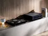 A turntable and amplifier are displayed on a shelf with a wooden background. Produktbild-Vorschau